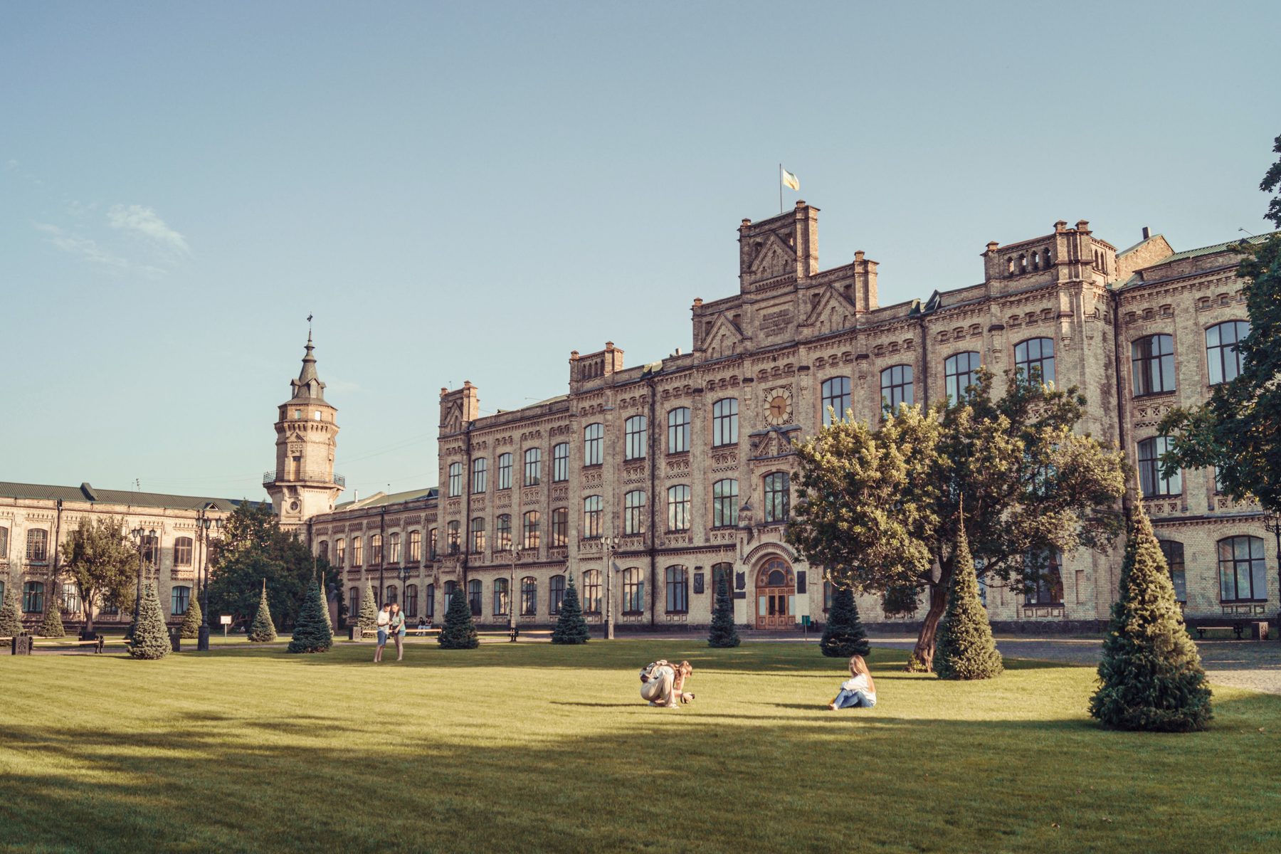 A historic collegiate building at golden hour, framed by lawns and trees