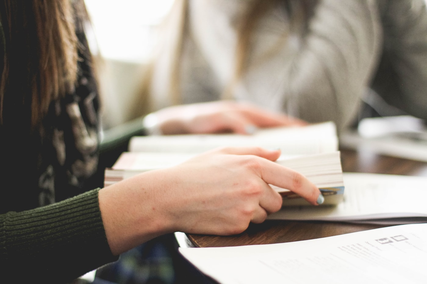 Two people reading closely together over open books, in the one-to-one tutorial tradition
