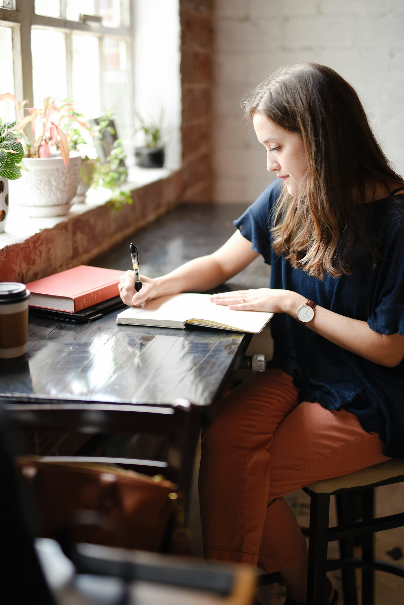 A student writing by hand at a sunlit window