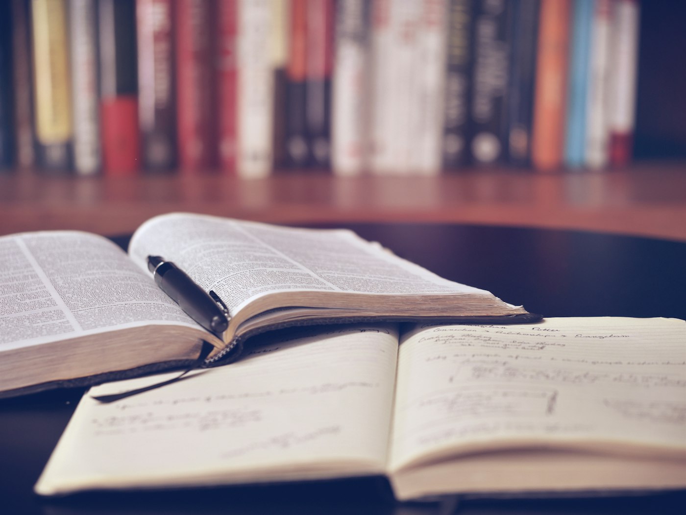 An open reference book and a notebook full of handwritten study notes