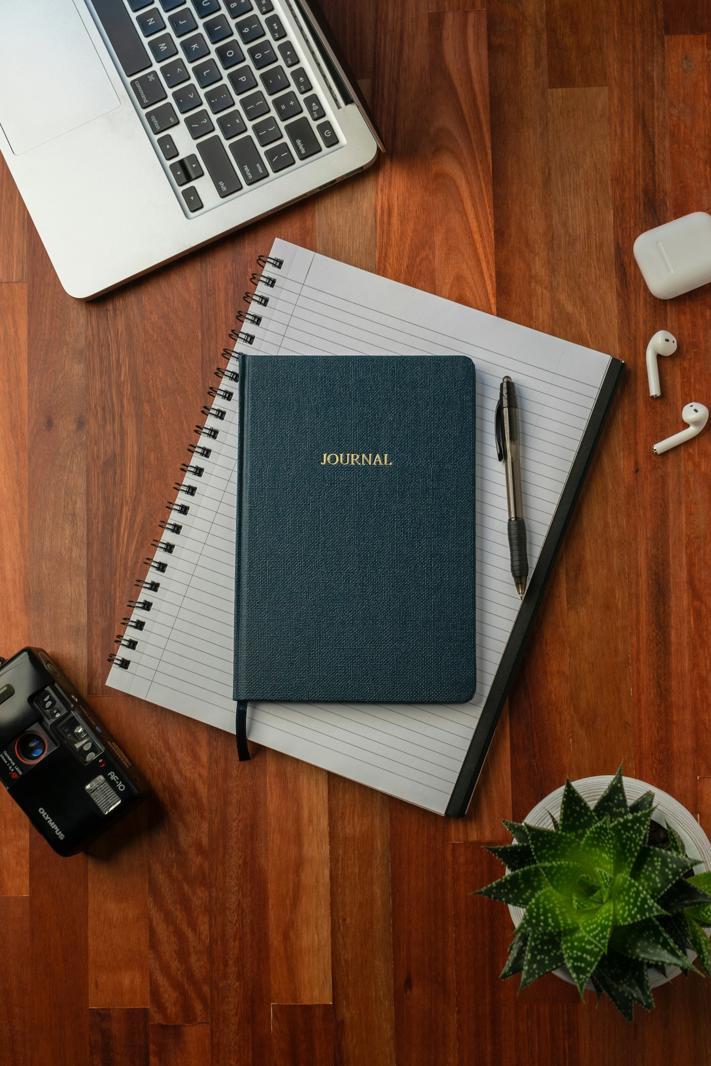 A leather journal and notebook on a warm wooden desk