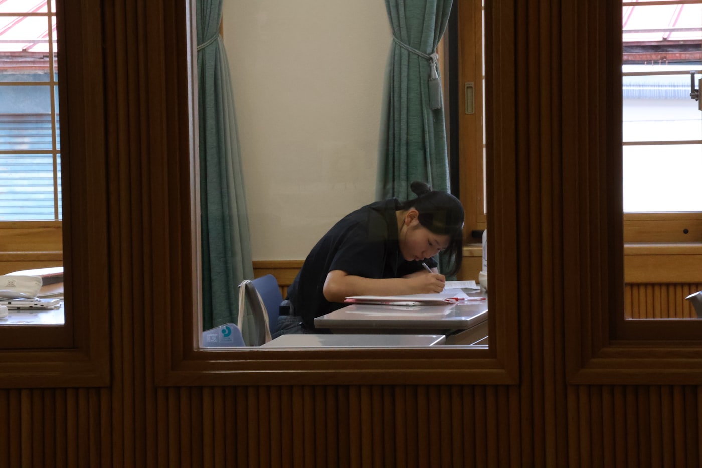 A student working intently at a desk in a quiet, wood-panelled library